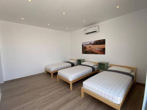 Al RamaCactus Dead Sea Jordan的配有白色墙壁和木地板的客房内的三张床
