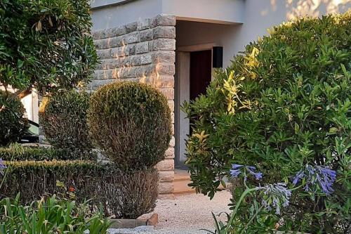 塞辛布拉Casa com jardim perto da praia的灌木丛房子的前门
