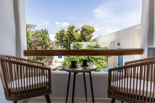 圣安娜纳克索斯Aesthete Suites的阳台配有两把椅子和一张桌子,上面有两张杯子