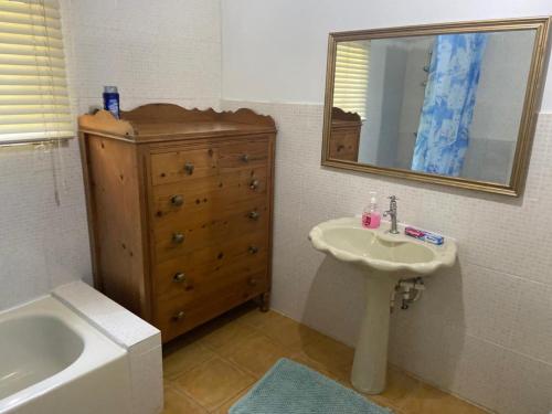 特雷热比奇Nat’s place的浴室配有盥洗盆、镜子和浴缸