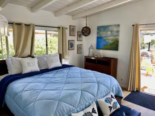 恩西尼塔斯Beach Style Home~Heart of Encinitas, Close to Beaches & Shopping的一间卧室设有蓝色的床和窗户。