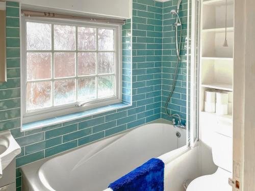利普胡克Garden Cottage 2 - Uk42882的蓝色瓷砖浴室设有浴缸和窗户。