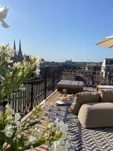 波尔多Hôtel Singulier Bordeaux的阳台配有沙发,享有城市景观