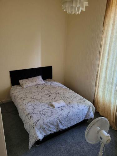 格拉斯哥Cosy Glasgow Southside Flat的卧室配有带白色棉被的床和风扇