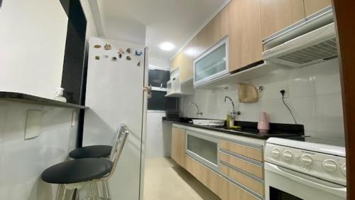 瓜拉派瑞Luxuoso a 250 Mts da Praia的小厨房配有白色冰箱和凳子