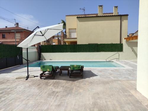 BáscaraCasa Empordà con piscina exclusiva的一个带两把椅子和白色遮阳伞的游泳池