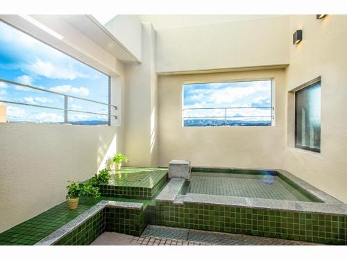 多治见市Kuretake Inn Premium Tajimi Ekimae的绿色瓷砖房子内的按摩浴缸
