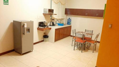 伊基托斯102 RV APARTMENTS IQUITOS-APARTAMENTO FAMILIAR CON PISCINA的厨房配有冰箱和桌椅