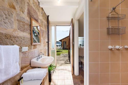 悉尼Newly Reburbished Sydney Harbourfront Boathouse Escape的一间带水槽和石墙的浴室