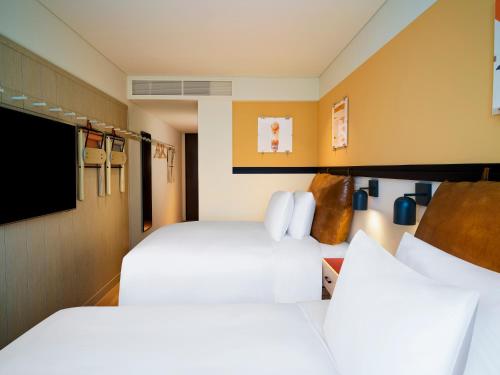 首尔Moxy Seoul Myeongdong的酒店客房设有两张床和一台平面电视。