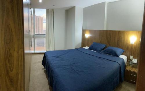 巴西利亚Promoção - Flat em Brasília的一间卧室设有蓝色的床和大窗户