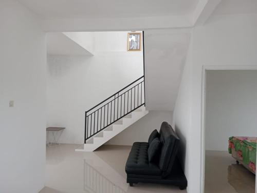 SonggoritiAPUT VILLA RESIDENCE MUTIARA B7的白色房间中的一张黑椅,设有楼梯