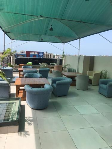 科托努Hotel Bel Azur Cotonou的一个带桌椅和绿色遮阳伞的庭院