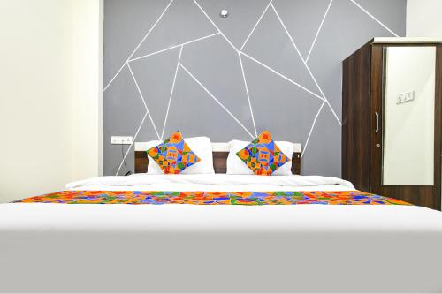 印多尔FabExpress SP7的一间卧室配有一张带色彩缤纷枕头的大床