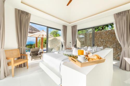 苏梅岛Beautiful 4 Bedroom Luxury Villa with Sea Views- KBR2的一间房间,里面设有一张床和一张桌子,上面有一只猫