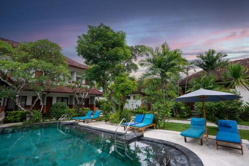 勒吉安Sinar Bali Hotel的一个带蓝色椅子和遮阳伞的游泳池