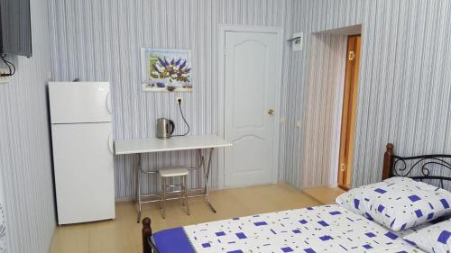加格拉Guest House Gorny Ruchei的一间卧室配有一张床铺、一张桌子和一台冰箱