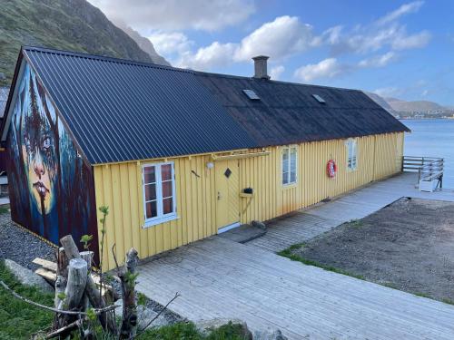 巴尔斯塔Kræmmervika Rorbuer - Rustic Cabins in Lofoten的黄色的建筑,在建筑的一侧画着画