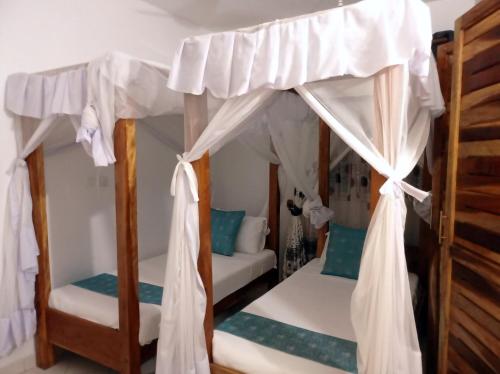 迪亚尼海滩Pendo Villas Diani Beach的一间卧室配有两张双层床和白色窗帘