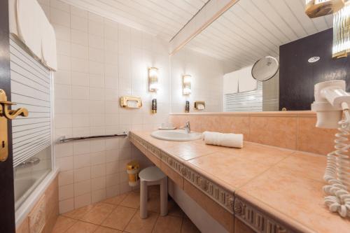 加舒恩普法伊费尔酒店的一间带水槽、浴缸和镜子的浴室