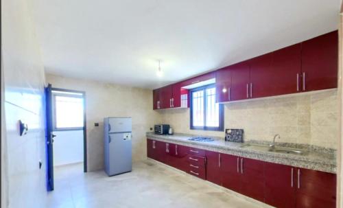达赫拉KHALIJ HOSPITALITE的一间带红色橱柜和冰箱的厨房