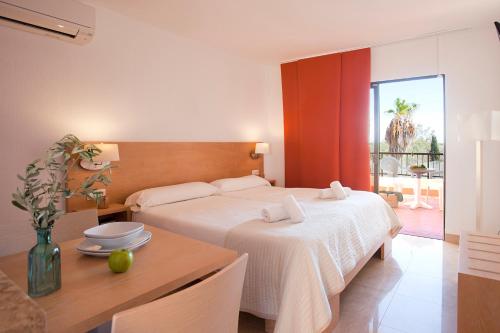 卡拉罗曼蒂卡Apartamentos Sol Romántica by DOT Suites的卧室配有白色的床和带桌子的西德克斯桌