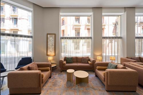 萨拉戈萨加泰罗尼亚支柱酒店的大堂配有沙发、桌子和大窗户。