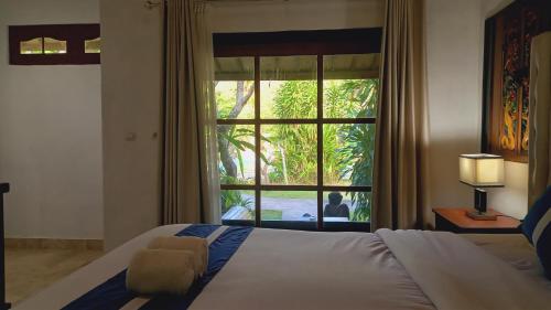 龙目岛库塔Matahari Inn Kuta Lombok的一间卧室设有一张床和一个大窗户
