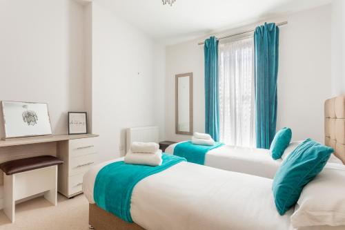 红山Castle Haven Apartment, Redhill的卧室内的两张床,配有蓝色窗帘