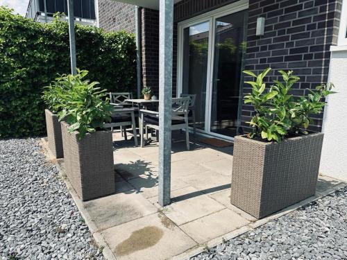诺德霍恩FeWo Am Ring - mit Terrasse的一个带桌子和两株盆栽植物的庭院