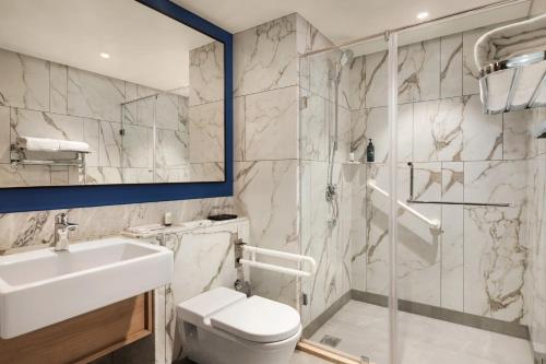 西里古里Ramada Encore by Wyndham Siliguri Sevoke Road的浴室配有盥洗盆、卫生间和淋浴。