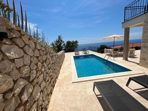 布德瓦Family Vacation Villa Rezevici的石墙旁边的游泳池