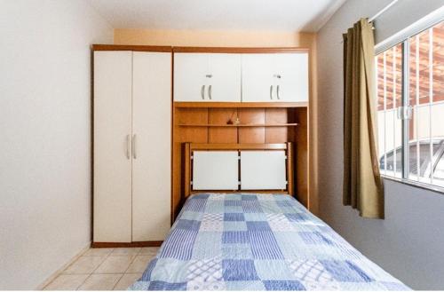 里约达欧特拉斯Casa aconchegante à 200m da praia的客房设有一张床、白色橱柜和窗户。
