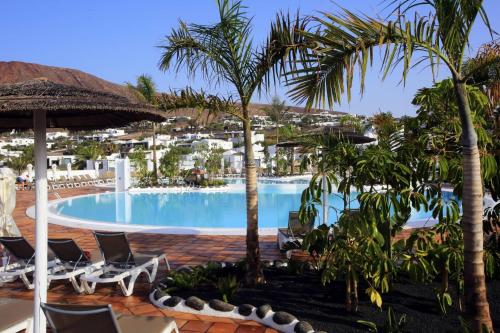 普拉亚布兰卡Labranda Alyssa Suite Hotel的棕榈树和椅子的度假村的游泳池