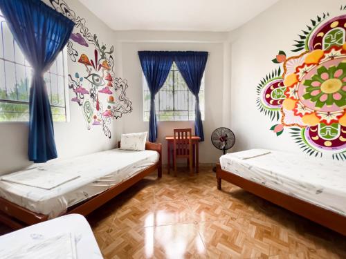 塔拉波托El Mural Backpackers的墙上壁画的房间里设有两张床