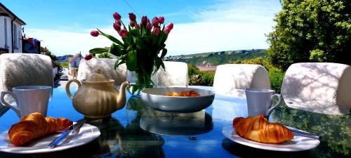 滨海比格伯里Bantham House, Bantham, South Devon - a few steps from golden sandy beaches的一张带羊角面包和花瓶的玻璃桌