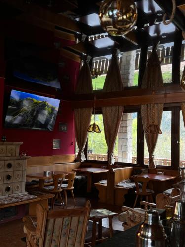 Albergo Monte RovereMonterovere的餐厅设有木桌、椅子和大窗户。