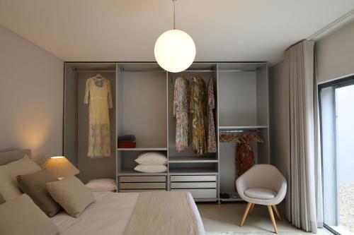 埃里塞拉Akivillas Ericeira Lullaby的一间卧室配有一张床、一把椅子和一个衣柜
