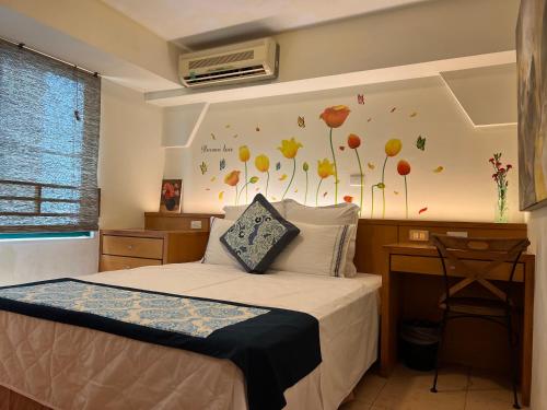 安平区台南运河民宿 的一间卧室配有一张带书桌的床和鲜花的墙壁