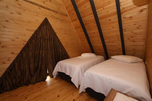 PelitliAzhara Bungalov的小木屋内带两张床的房间