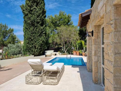 库克里亚EXQUISITE GOLF VILLA with Sea, 8Tee, Green Views, in Aphrodite Hills Golf Resort的一个带两把椅子的庭院和一个游泳池