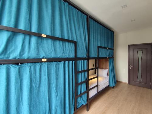 博尔若米ATI MTA - Eco Hostel的一间卧室配有两张双层床和蓝色窗帘