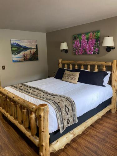 Summit Lake苏米特湖畔旅舍的一间卧室配有一张带白色床单和鲜花的木制床。