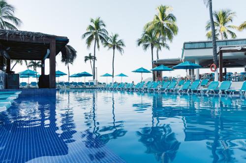 伊斯塔帕丰唐伊斯塔帕酒店的一个带椅子和遮阳伞的游泳池以及棕榈树