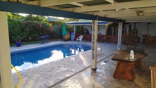 普纳奥亚Maison de vacances avec piscine et accès plage de sable blanc的一个带桌子和遮阳伞的游泳池