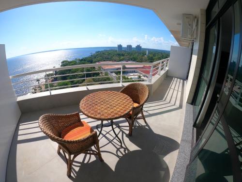 马瑙斯Tropical Executive Hotel的阳台配有2张桌子和椅子,享有海景。