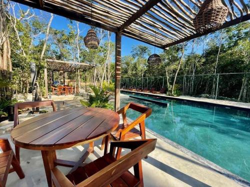 图卢姆Estudio completo en la selva的游泳池旁的一张木桌和椅子