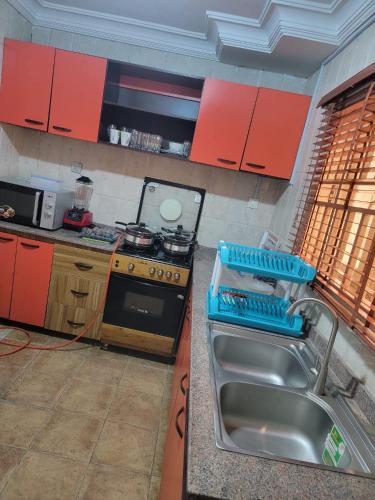 莱基S&M HOUSE的厨房配有水槽、炉灶和红色橱柜。