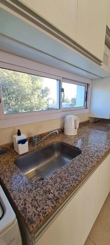 维拉阿连德Departamento Temporario - Barrio San Isidro (Malibu)的带水槽的厨房台面和2扇窗户