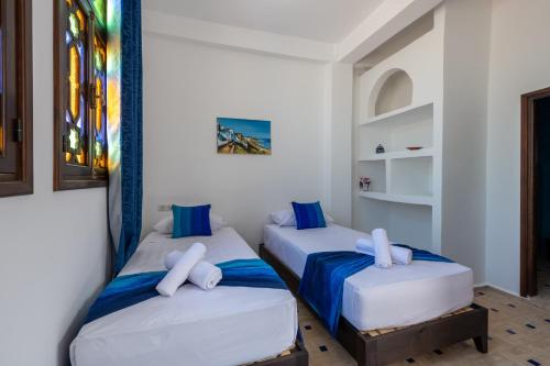 丹吉尔Riad SULTANA的蓝色和白色的客房内的两张床